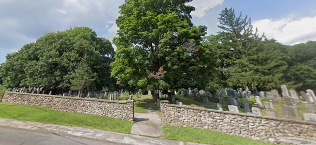 Brass City Lodge Cemetery grounds with stone wall and gravestones
